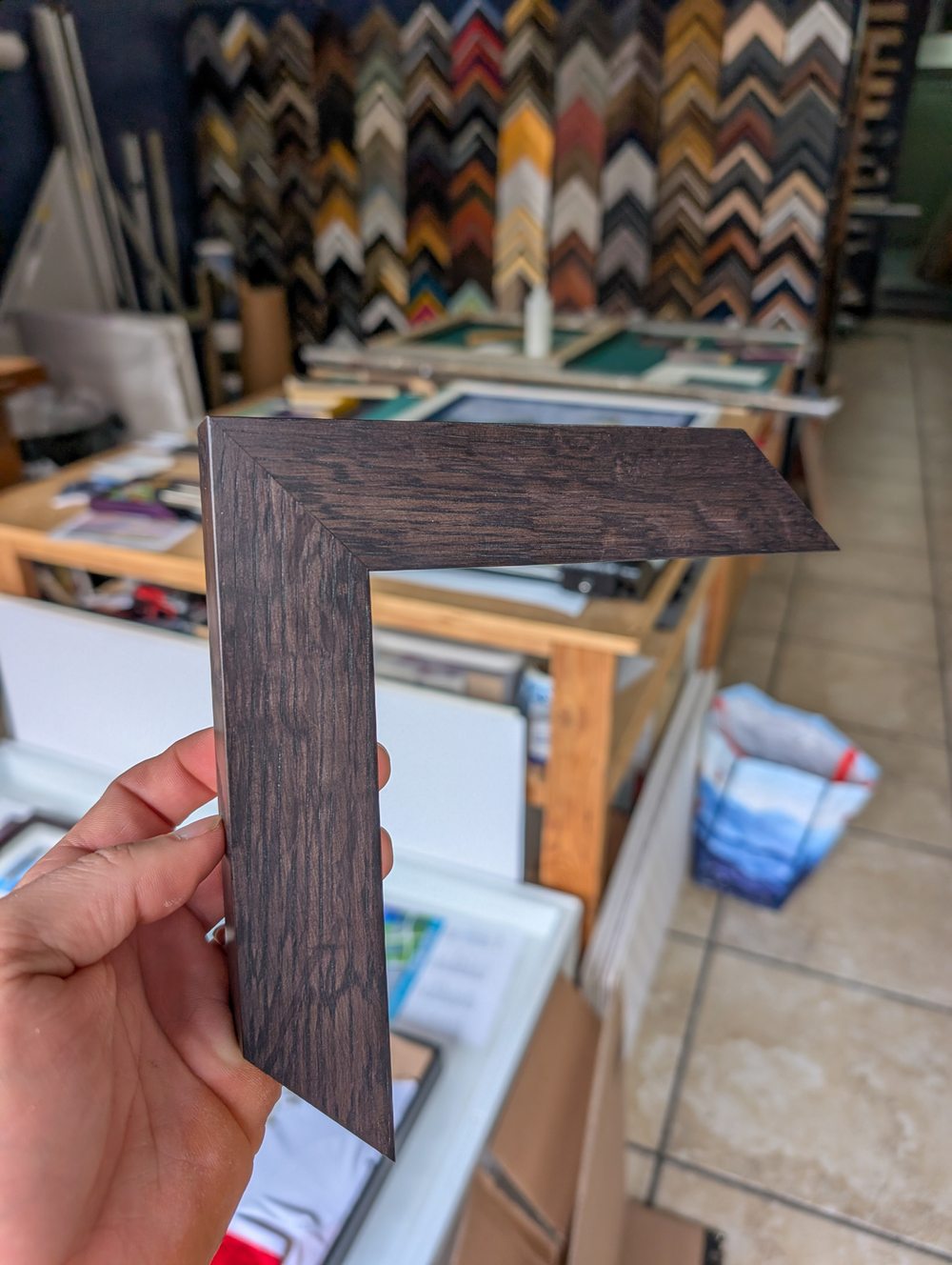 Hand holding a dark wood frame corner sample